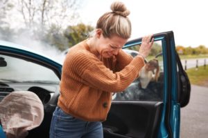 A woman holding her neck in pain while getting out of a car