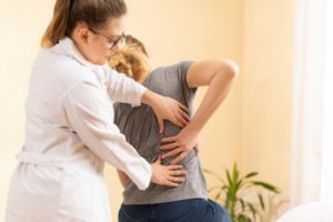 A woman showing a doctor where her back pain is located