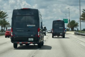 multiple Amazon delivery trucks driving on the highway