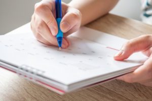 A close-up of a person's hand writing in a notebook