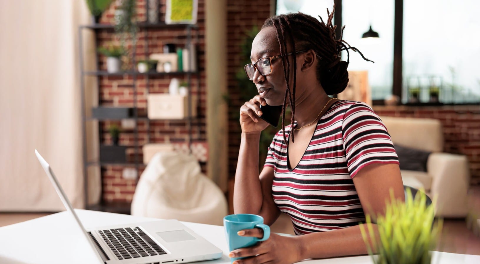 A person on the phone while viewing a laptop computer