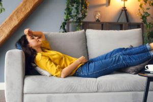 A woman lying on the couch with a headache