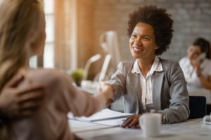 A client smiling and shaking hands with a personal injury lawyer